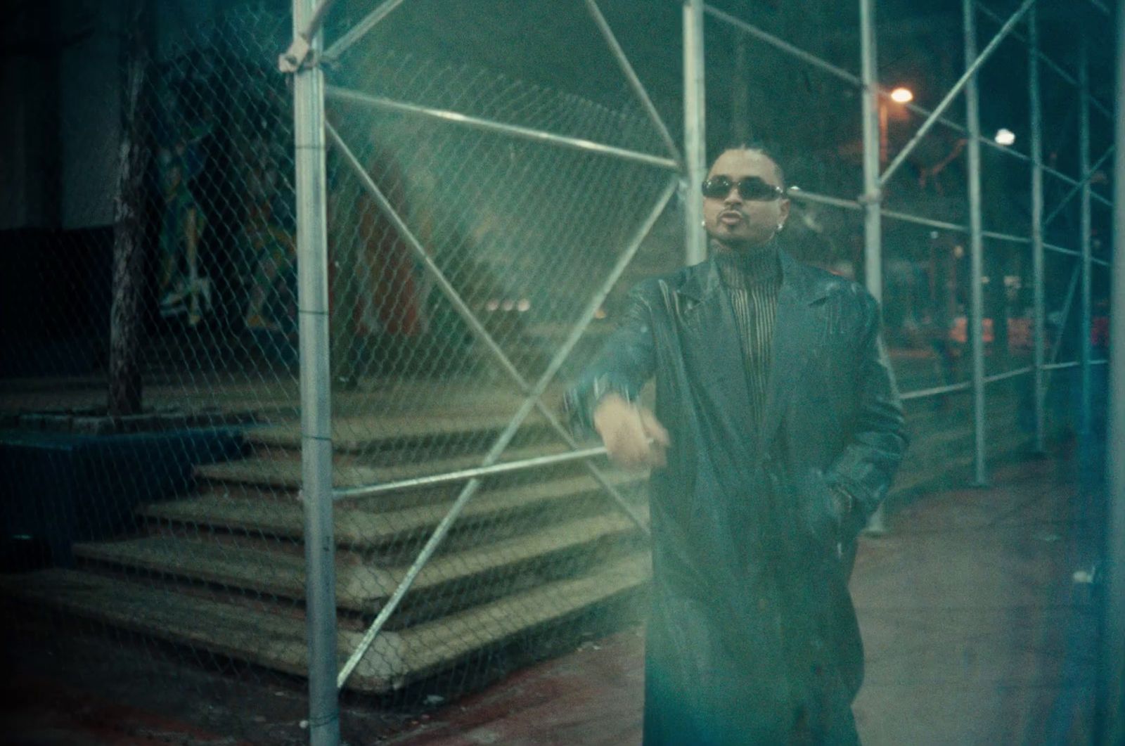 a man standing in front of a fence at night