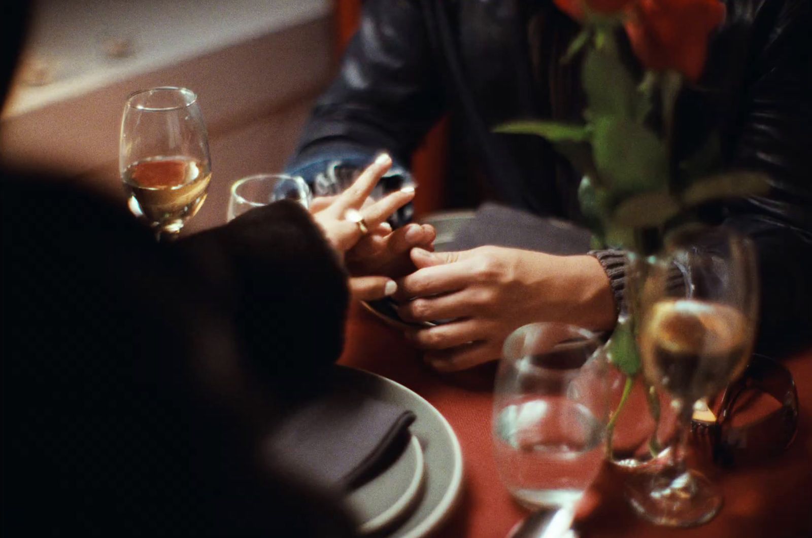 a man and a woman sitting at a table holding hands