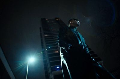 a man standing in front of a tall building at night