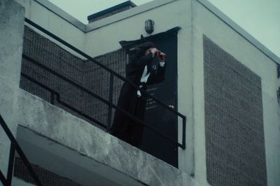 a man standing on a balcony holding a cell phone