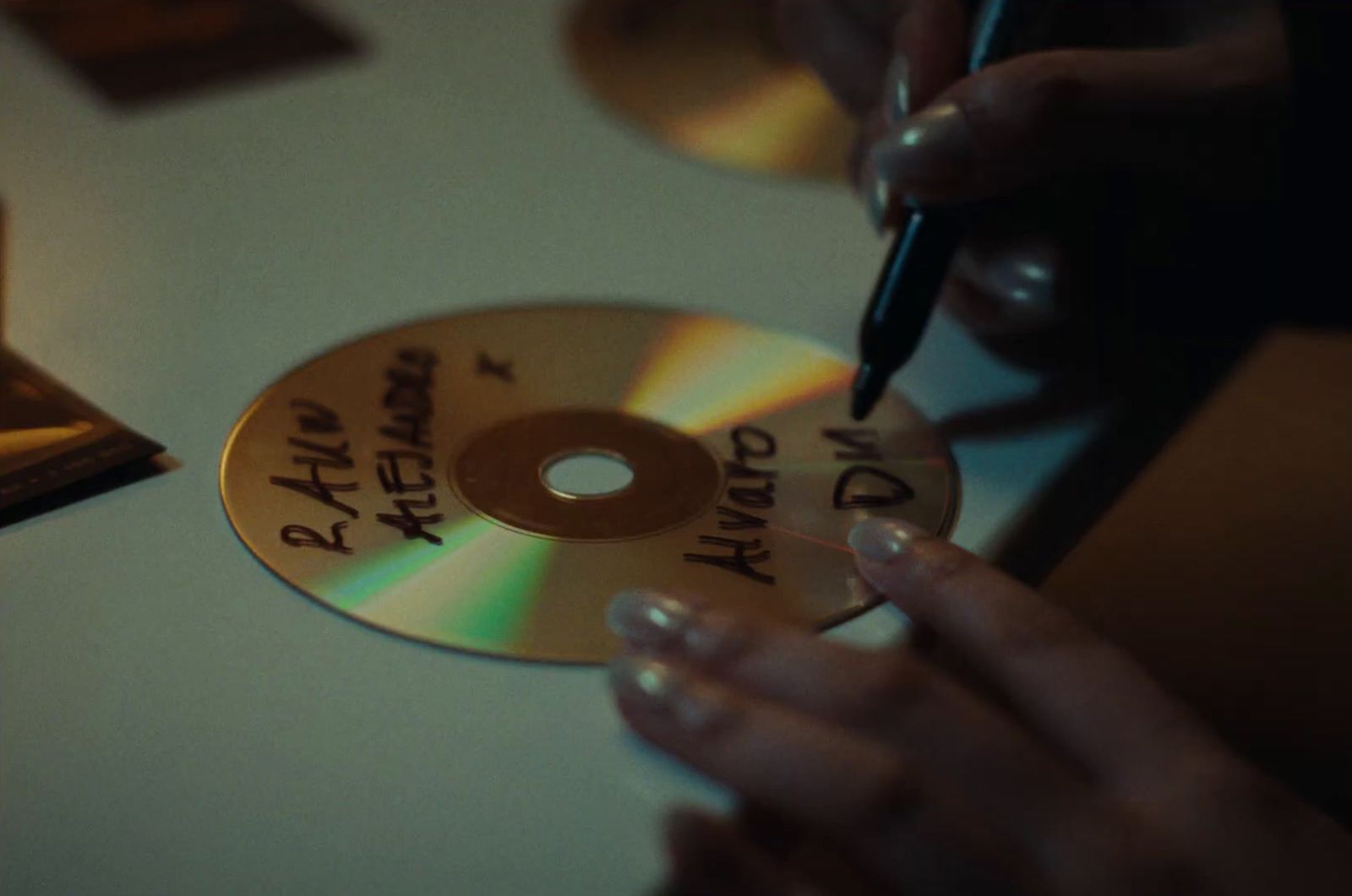 a person writing on a cd with a pen