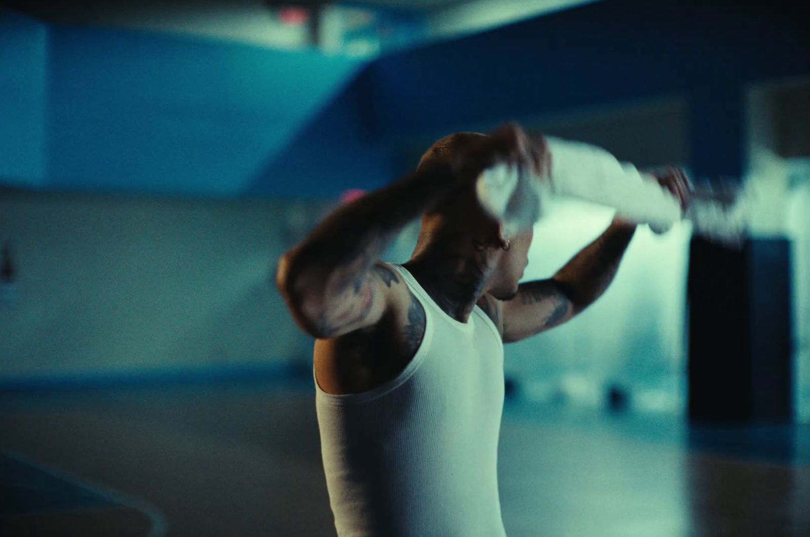 a man in a white tank top holding a white frisbee