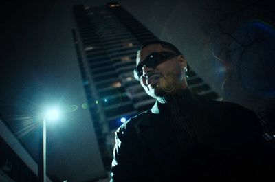 a man wearing sunglasses standing in front of a tall building