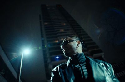 a man standing in front of a tall building at night