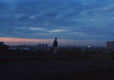 a man standing on top of a roof with a city in the background