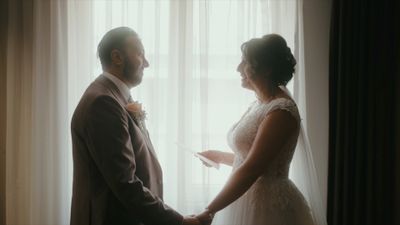 a bride and groom standing in front of a window