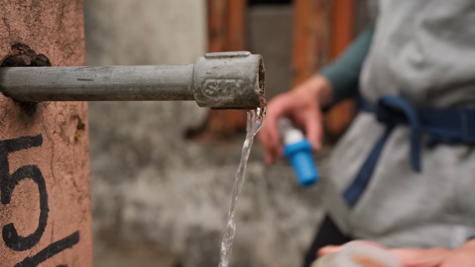 a person pouring water from a water faucet