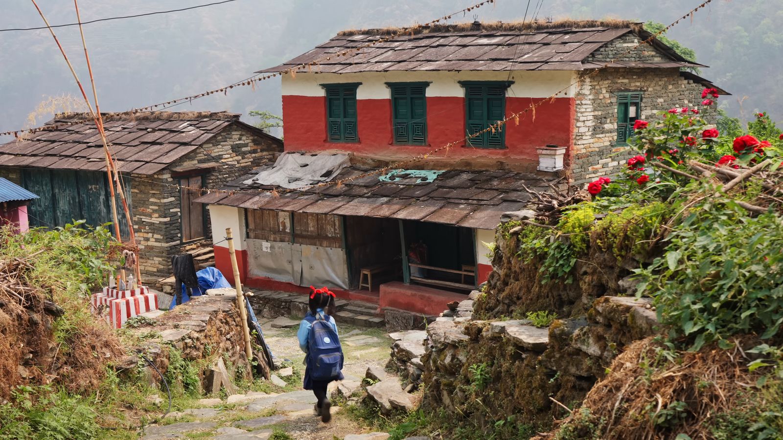 a woman walking down a stone path in front of a building