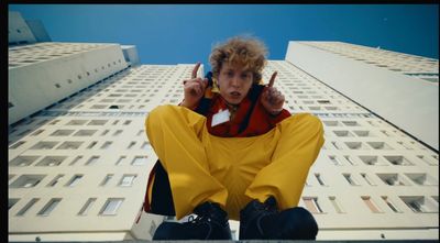 a young man sitting on a ledge talking on a cell phone