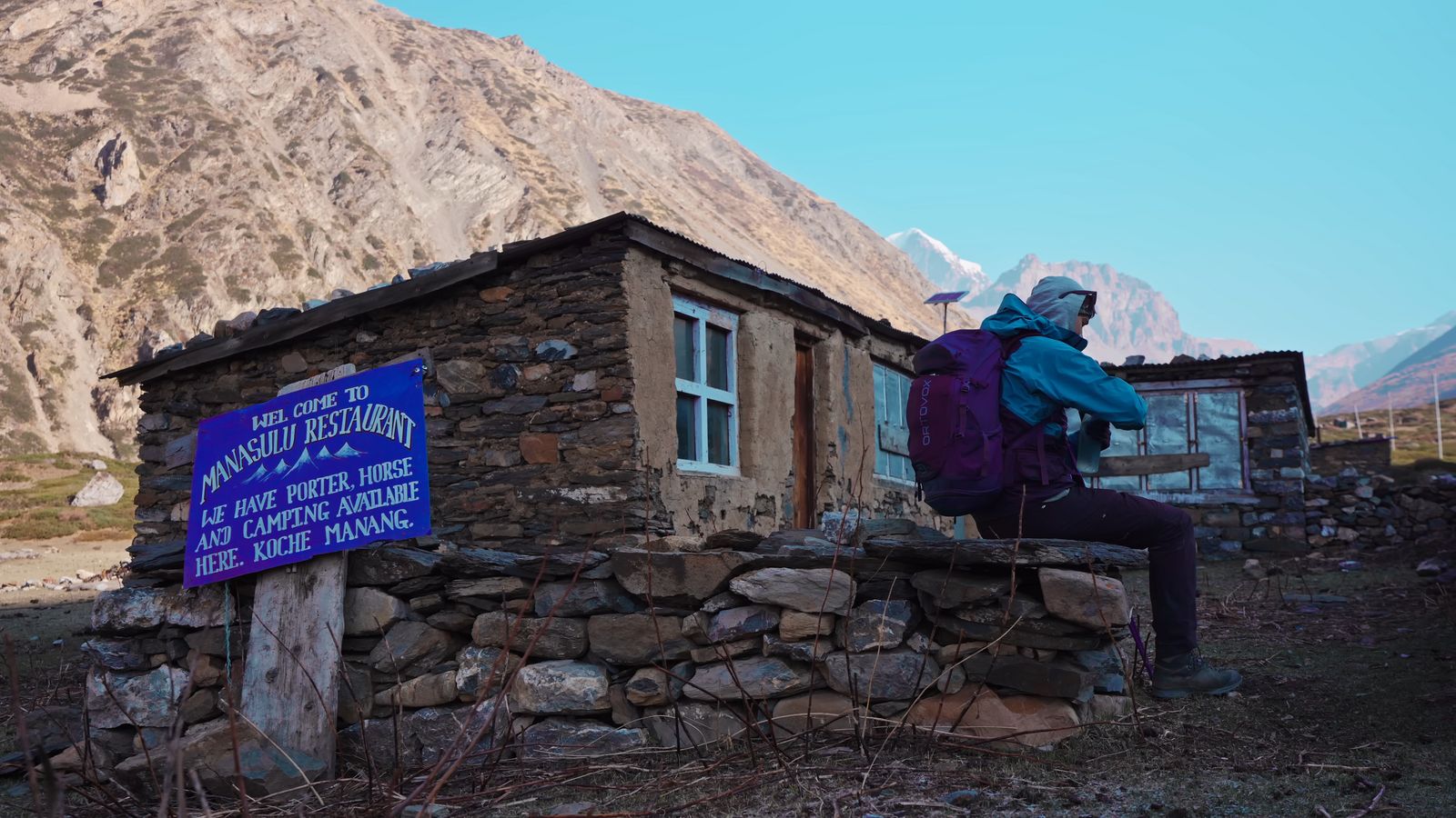 a person sitting on a rock wall near a building