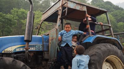 a group of children standing on the back of a tractor