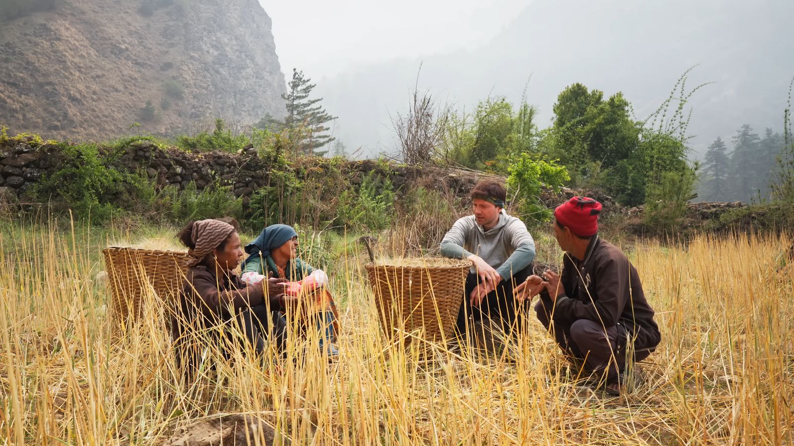 a group of people sitting on top of a grass covered field