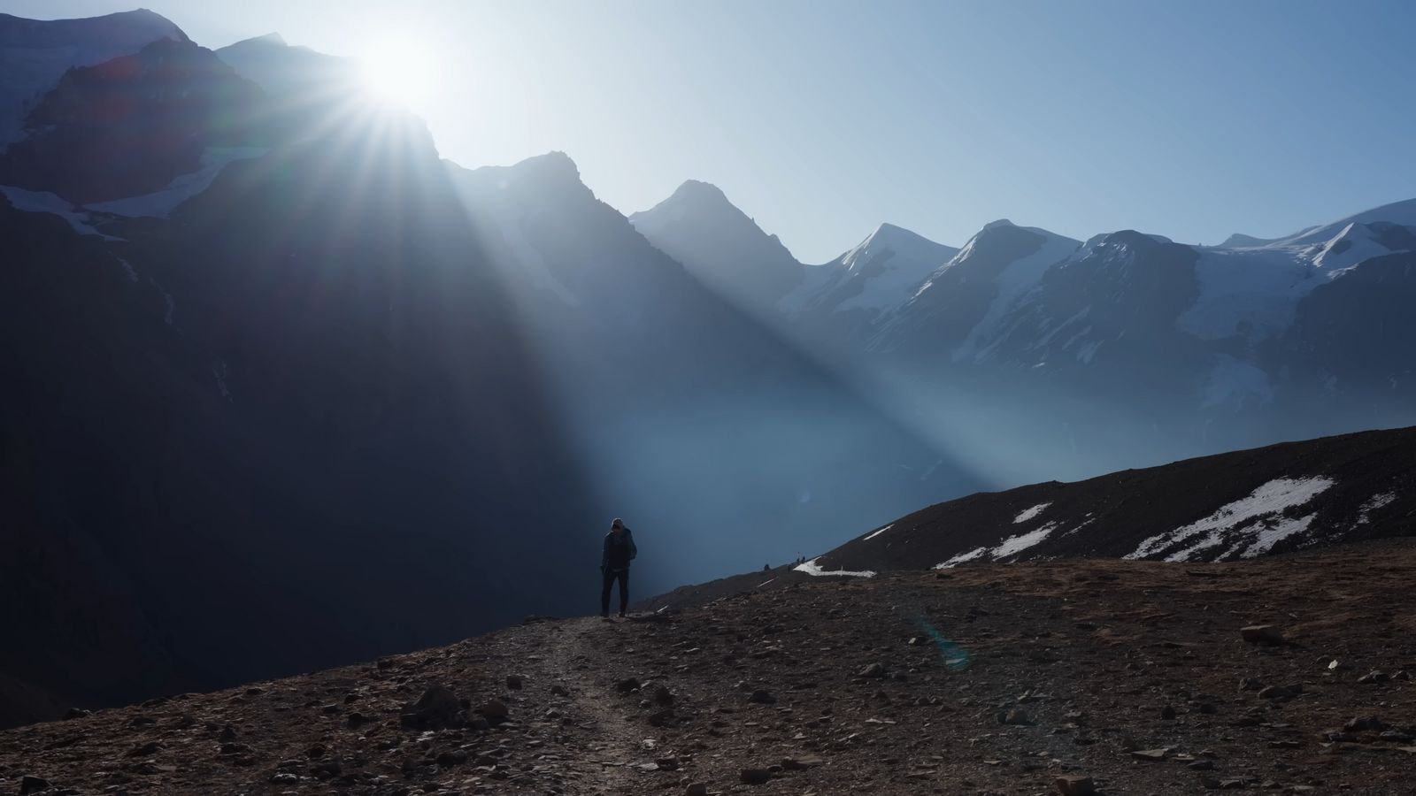 a person standing on a dirt road in the mountains