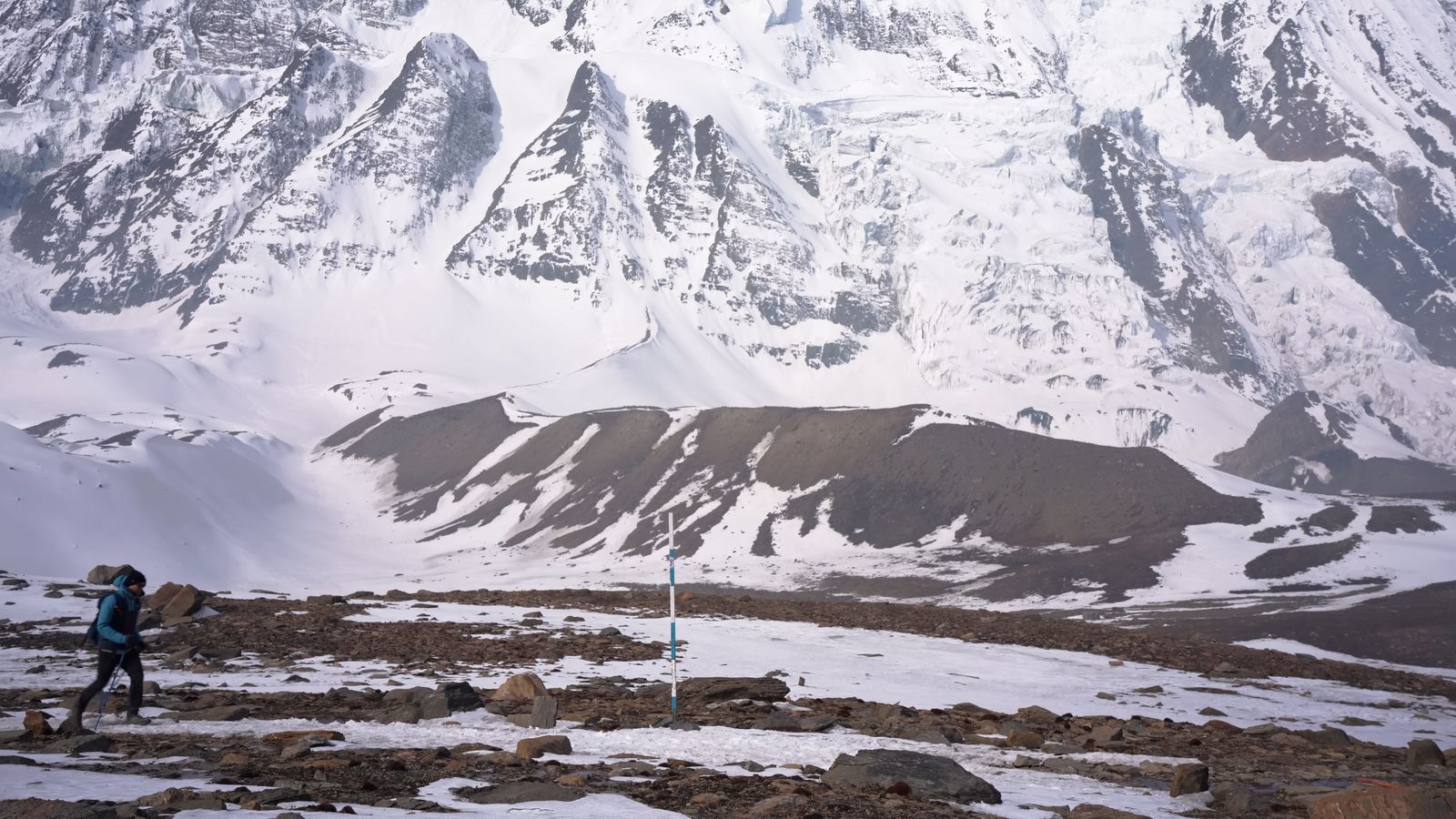 a person hiking up a snowy mountain with mountains in the background