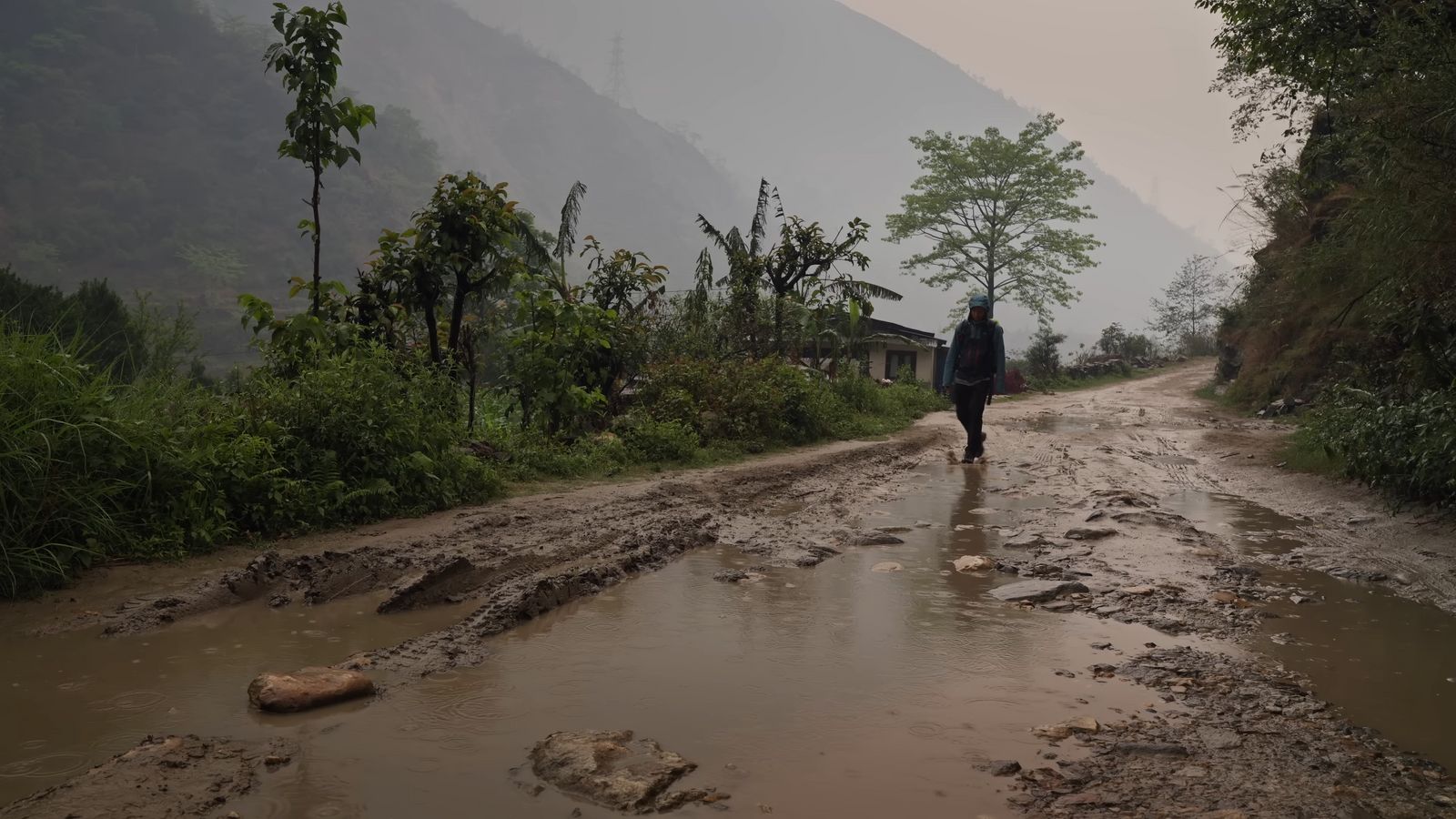 a person walking down a muddy road in the rain