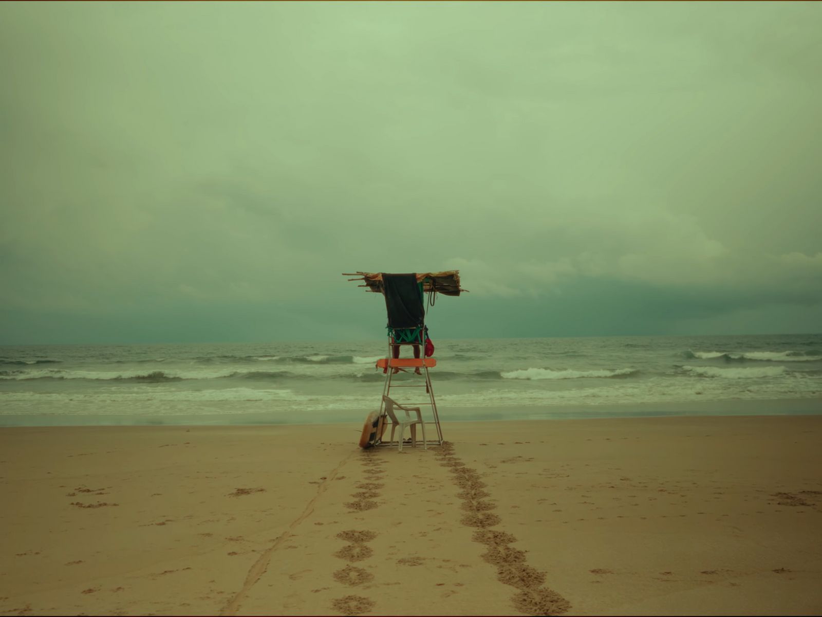 a man standing on top of a chair on top of a beach