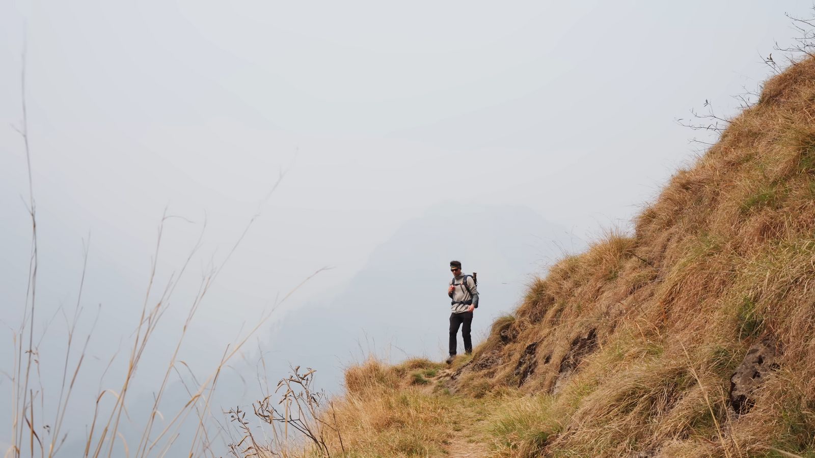 a man standing on top of a grass covered hillside