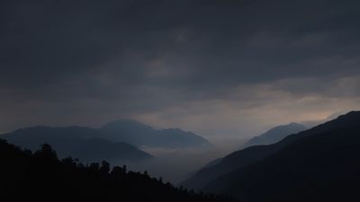 a dark sky with mountains in the background