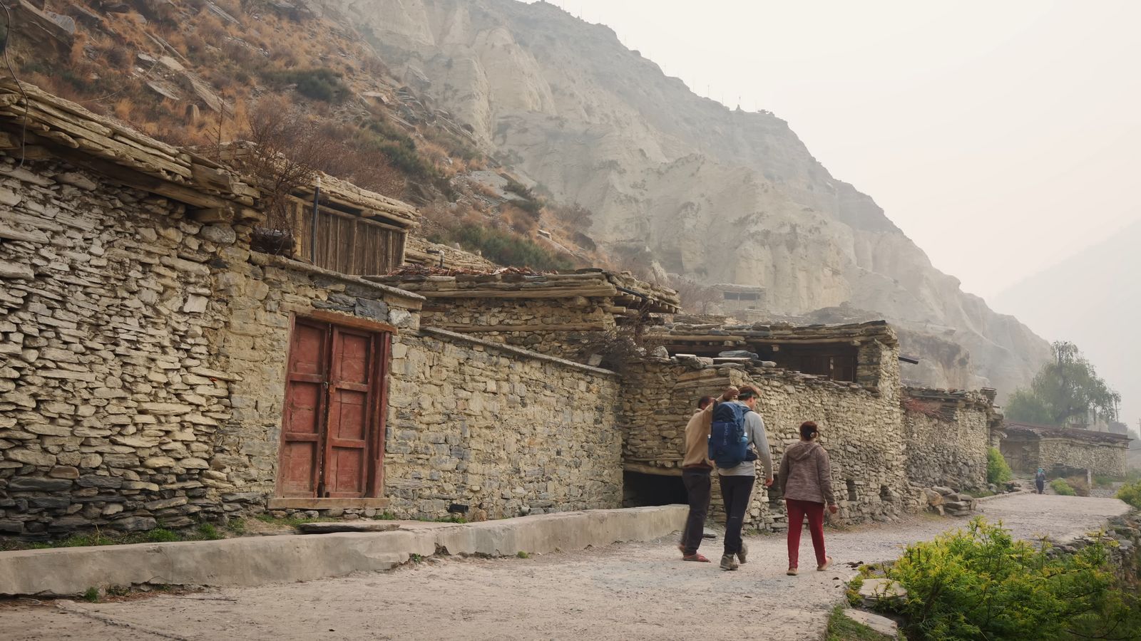 a couple of people walking down a dirt road