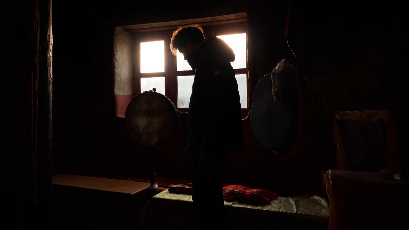 a woman standing in front of a window in a dark room