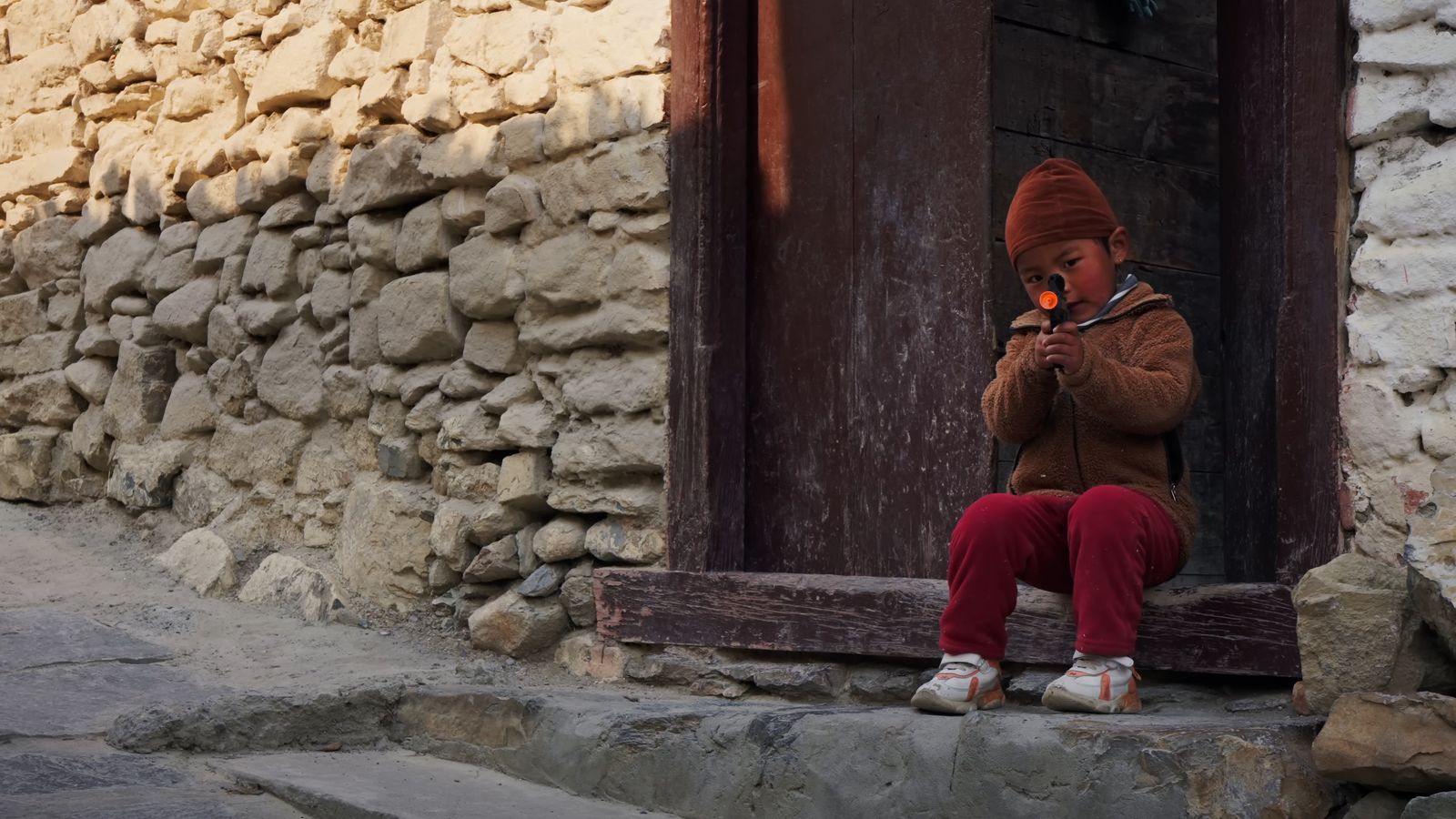 a little girl sitting on a window sill next to a stone building