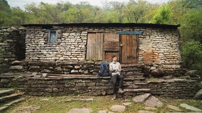 a man sitting outside of a stone building