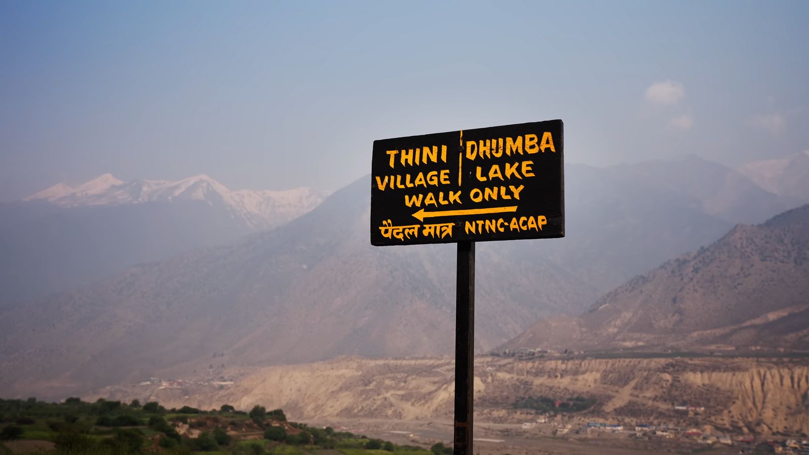 a sign on a pole with a mountain in the background