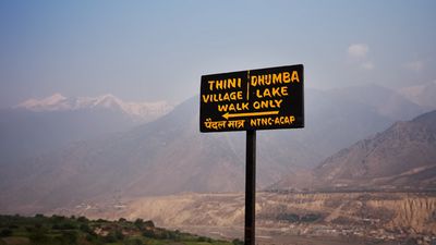 a sign on a pole with a mountain in the background