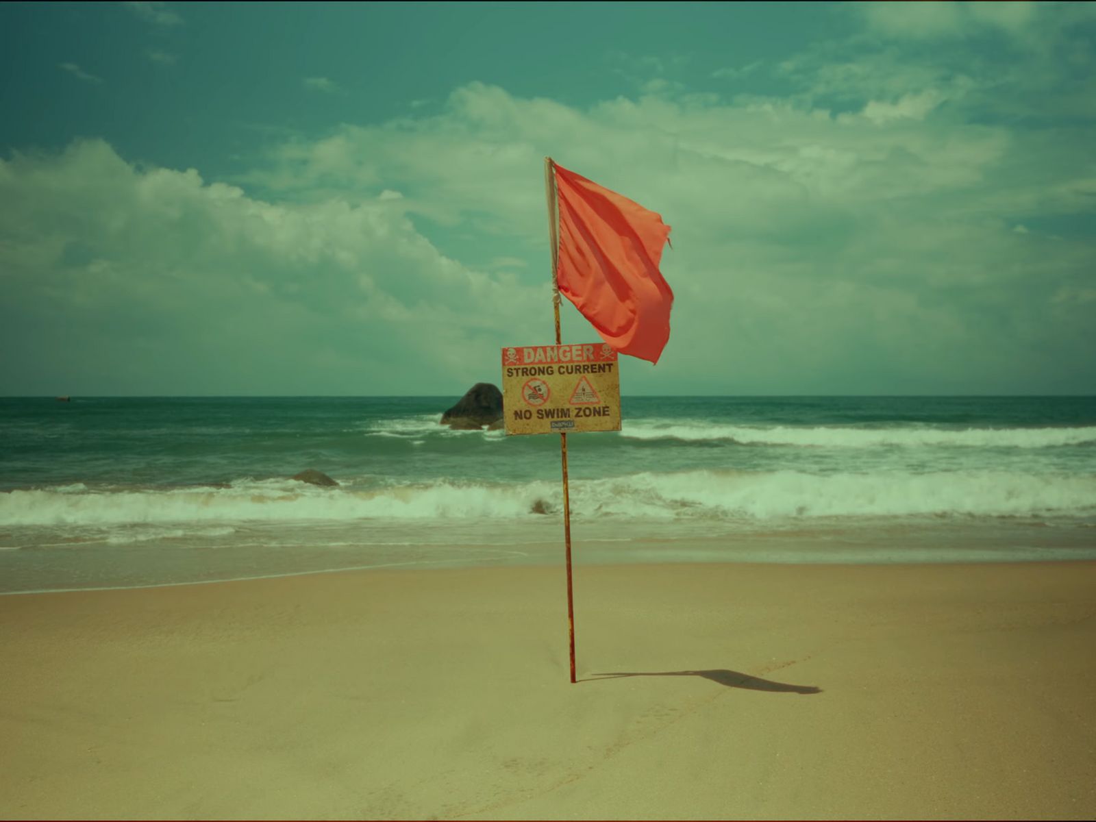 a red flag on a beach next to the ocean