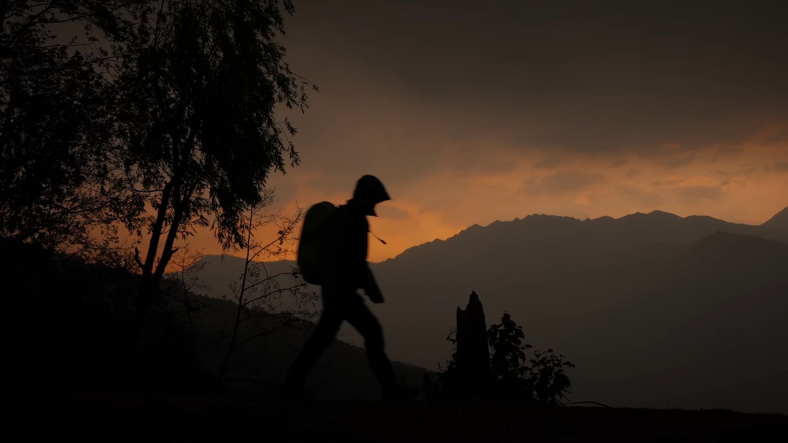 a man with a backpack walking in the dark