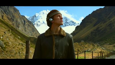 a man wearing headphones standing in front of a mountain