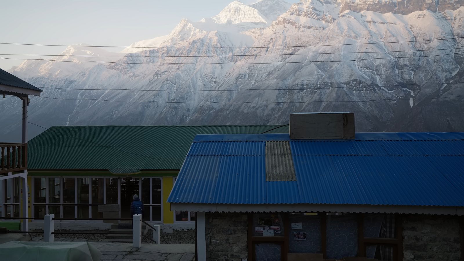 a building with a blue roof and a mountain in the background