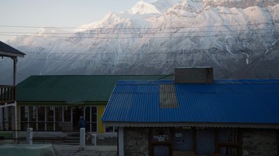 a building with a blue roof and a mountain in the background