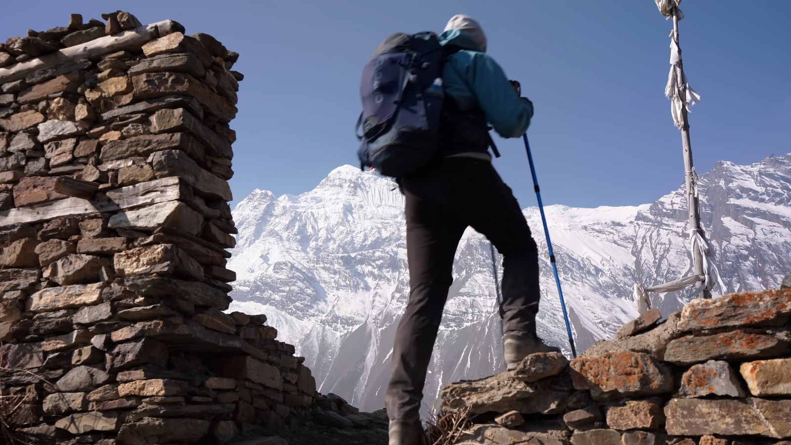 a man with a backpack is standing on a rock wall