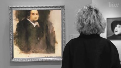 a woman looking at a portrait of a man