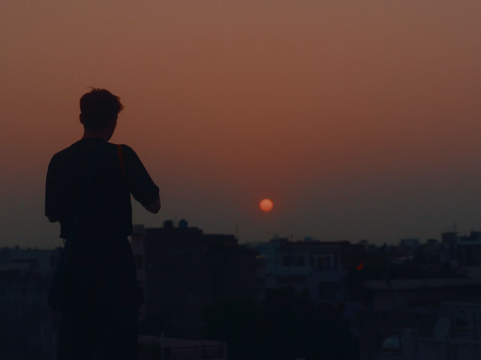 a man standing on top of a roof watching the sun go down