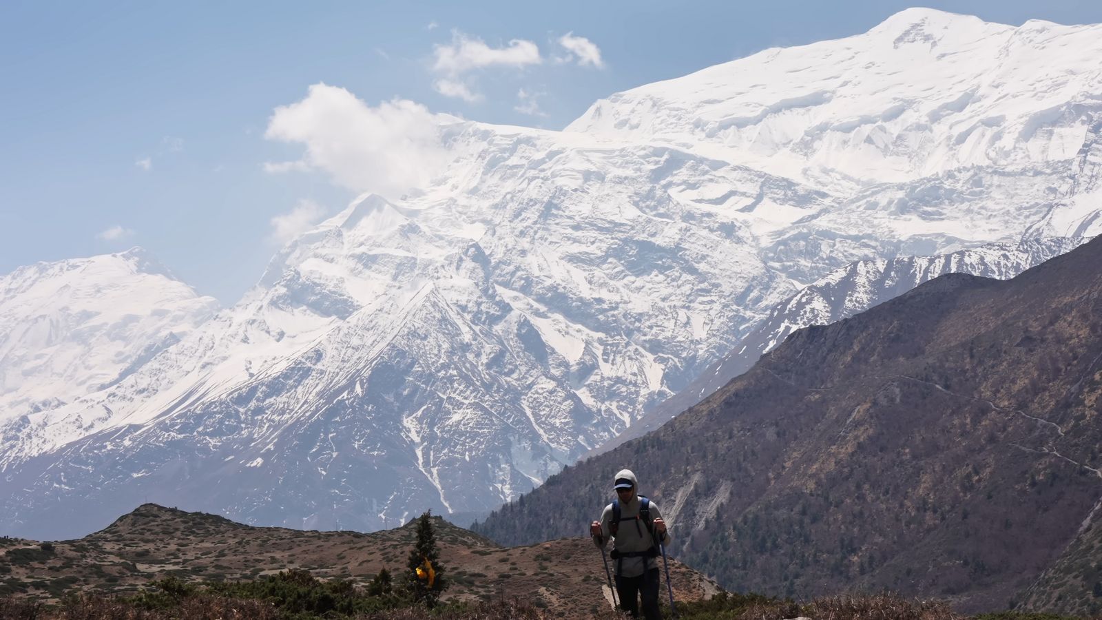 a man standing on top of a mountain with a snow covered mountain in the background