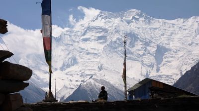 a man standing on top of a roof next to a tall snow covered mountain