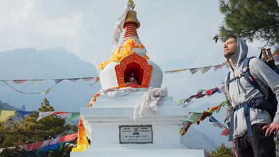 a man standing in front of a statue with a mountain in the background