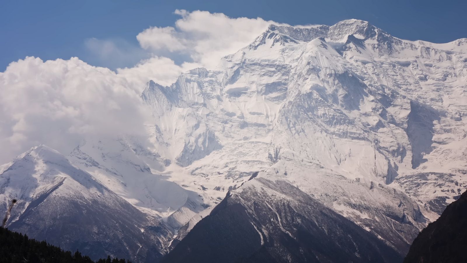 a large mountain covered in snow under a blue sky