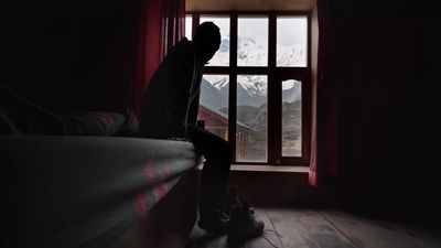 a person sitting on a bed looking out a window