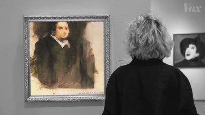 a woman looking at a portrait of a man