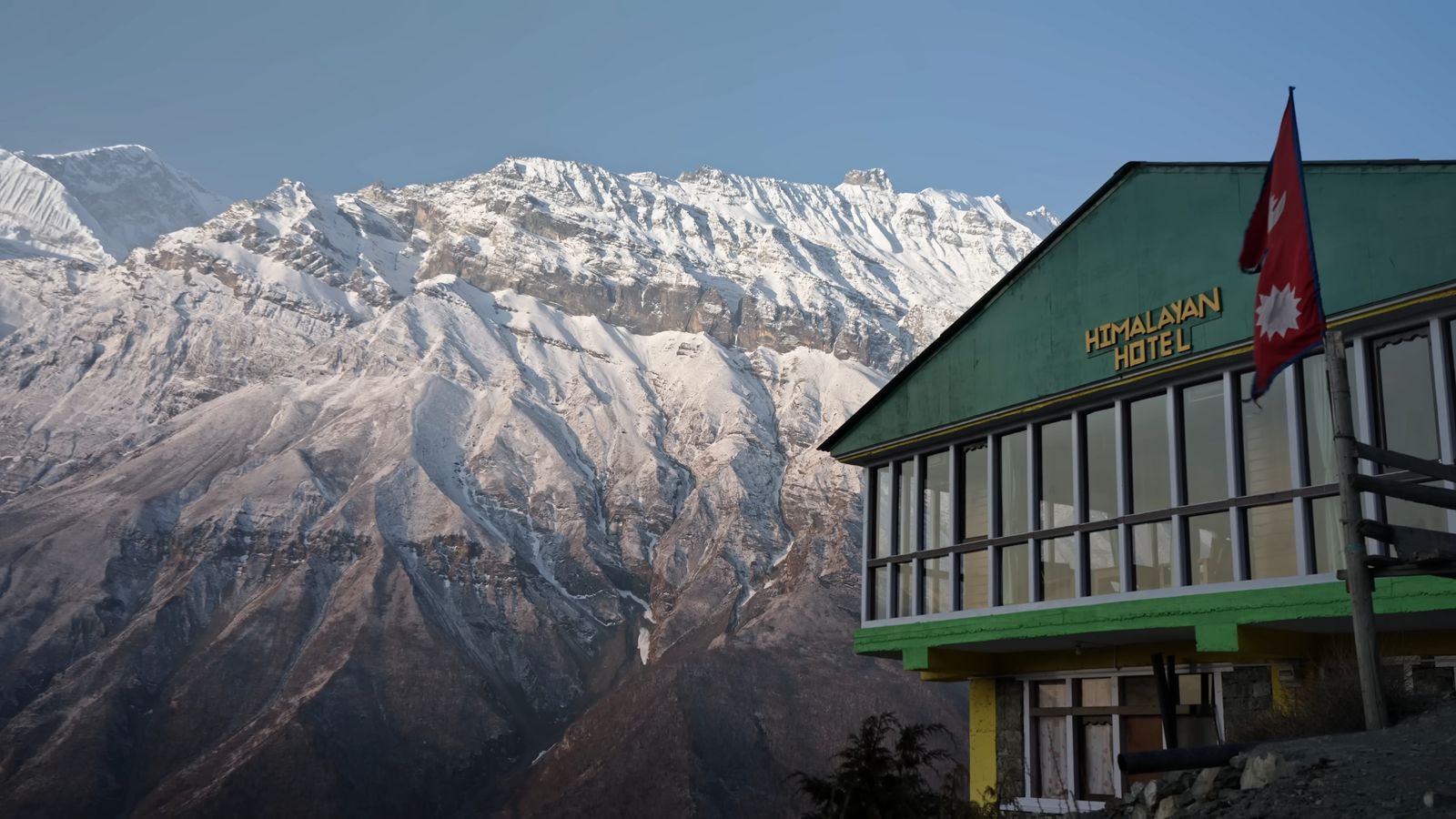 a building with a flag on top of it in front of a mountain