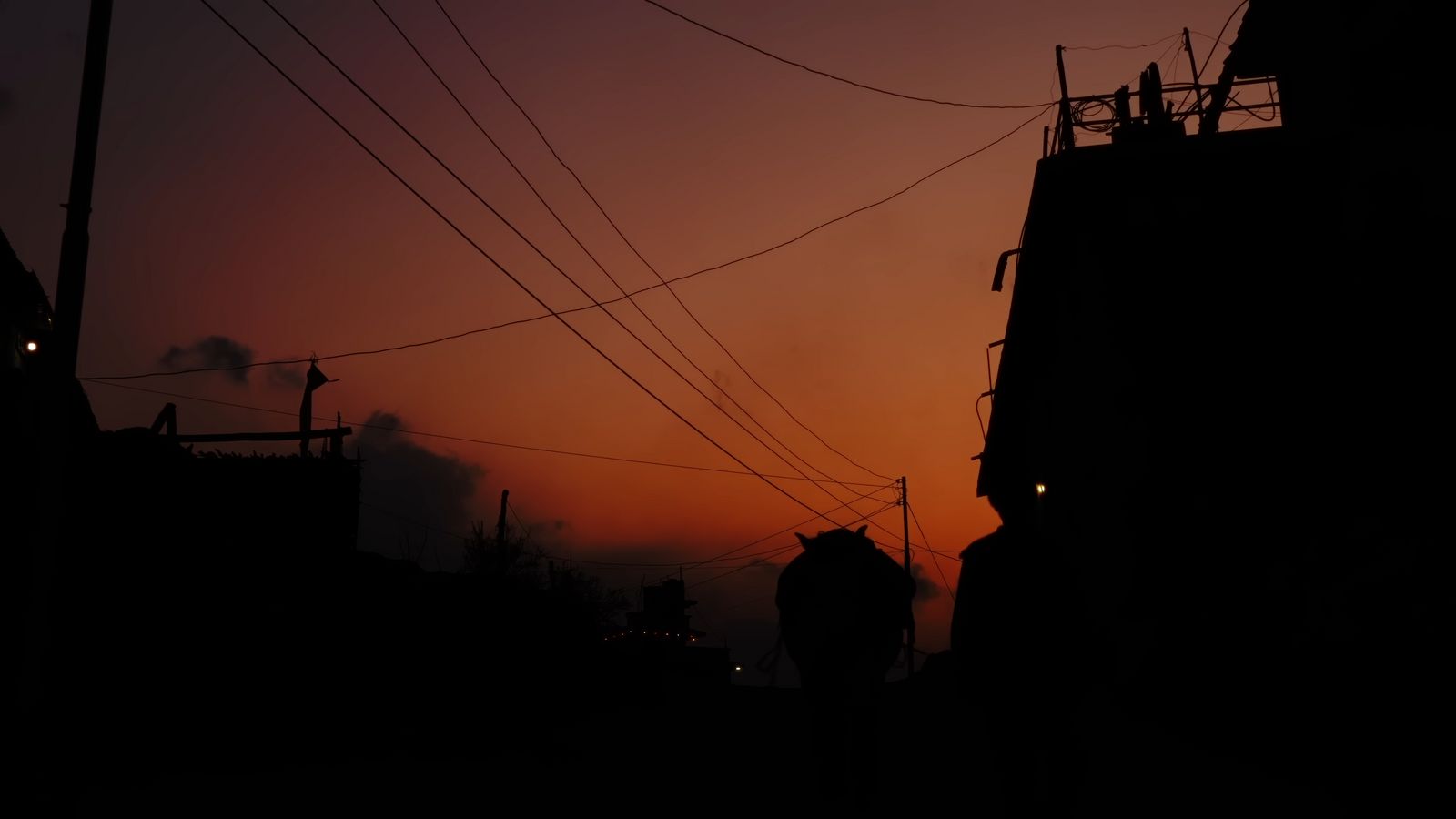 a silhouette of a building and power lines at sunset