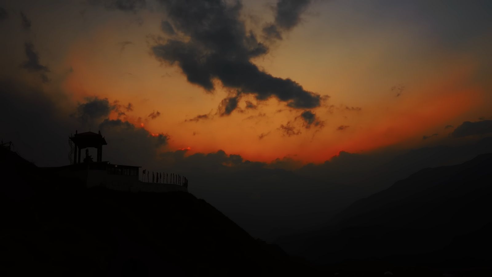 the sun is setting over a hill with a clock tower