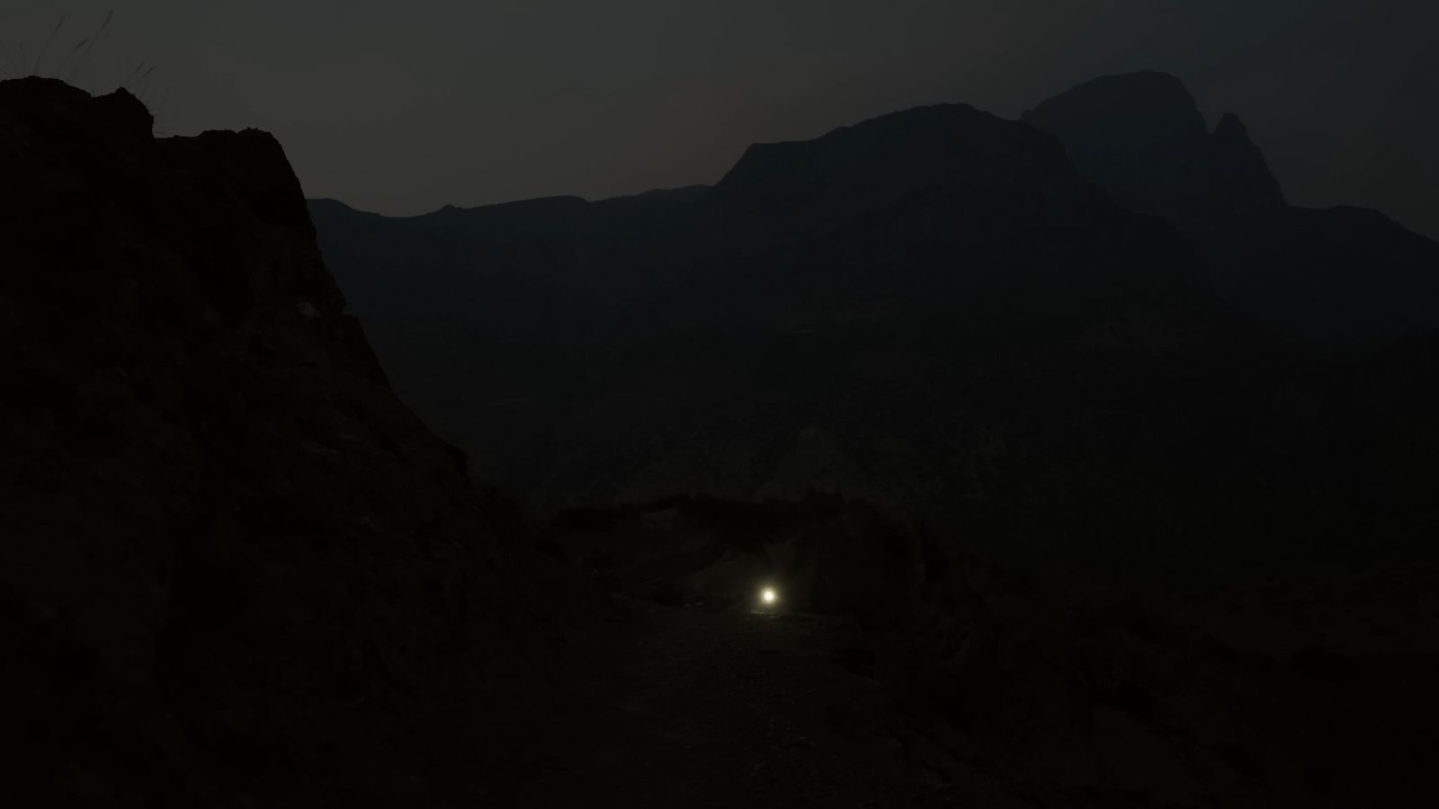 a dark mountain with a light at the end of it