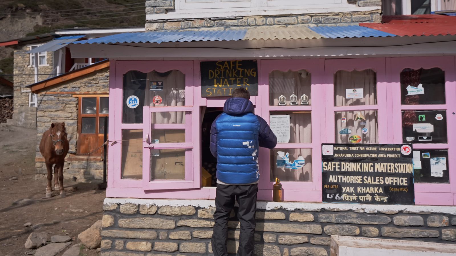 a man standing in front of a pink building