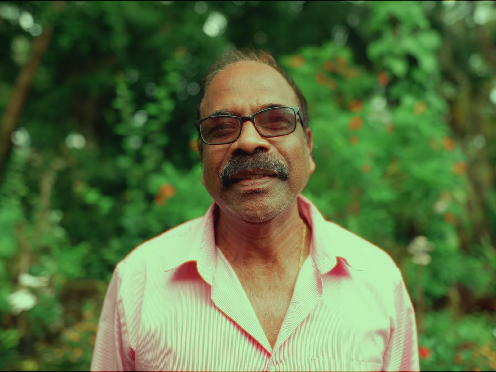 a man wearing glasses and a pink shirt