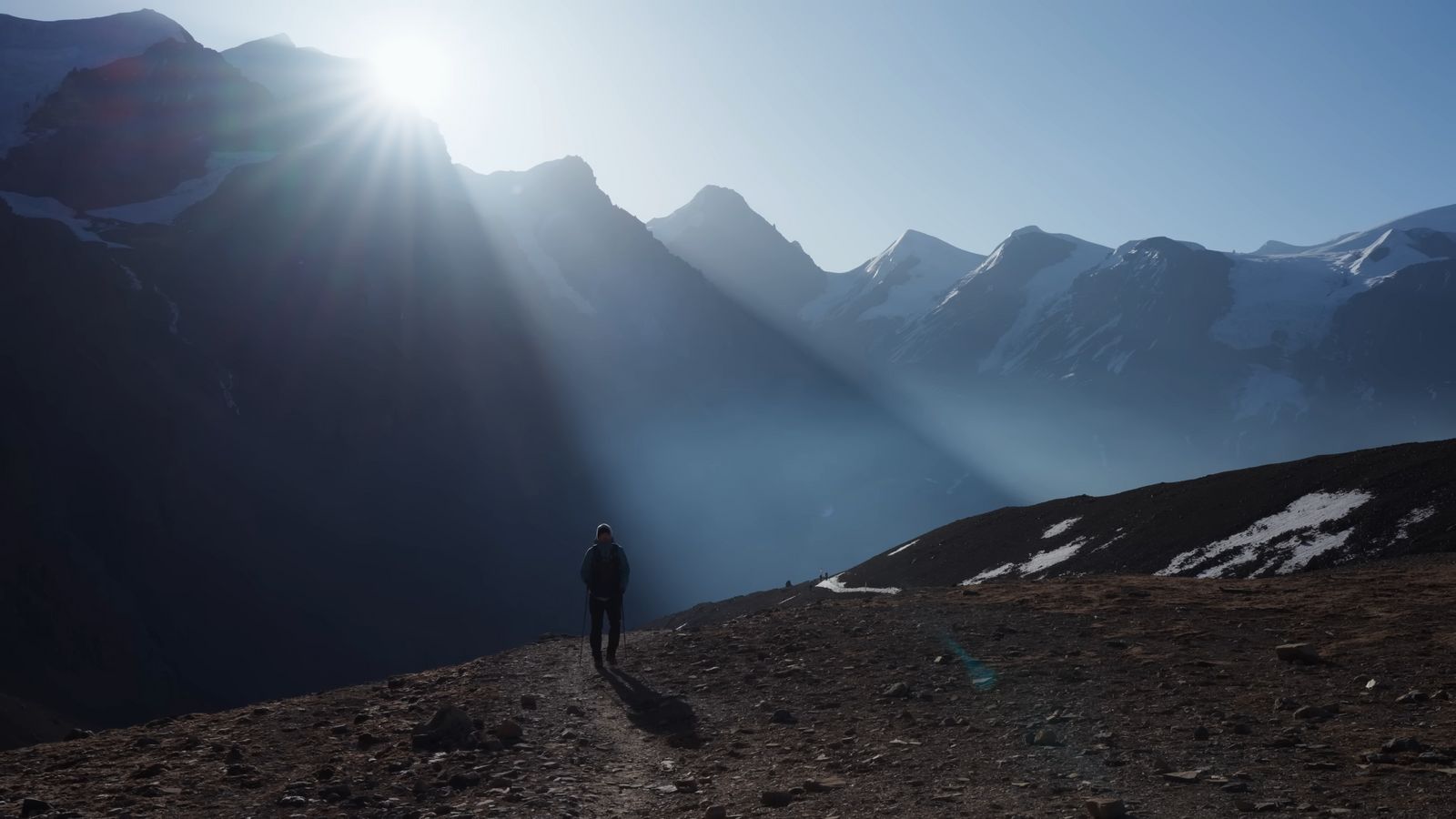 a man standing on top of a mountain under a bright sun