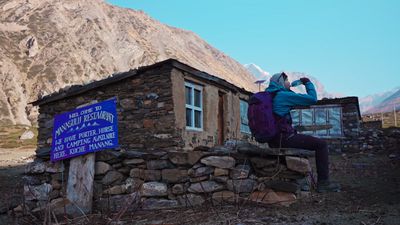 a woman standing on a rock wall next to a building